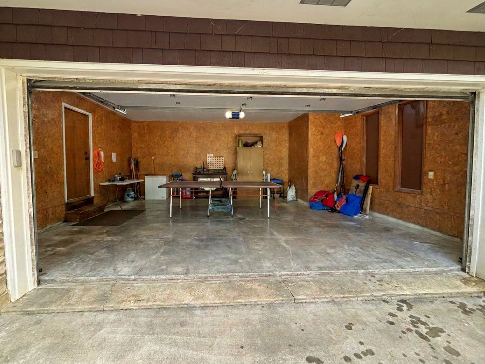 Signature Transformation before and after: dated garage turned into a premium lifestyle space with hexagon lighting, dark cabinetry, feature wall, and polished flake floor — before